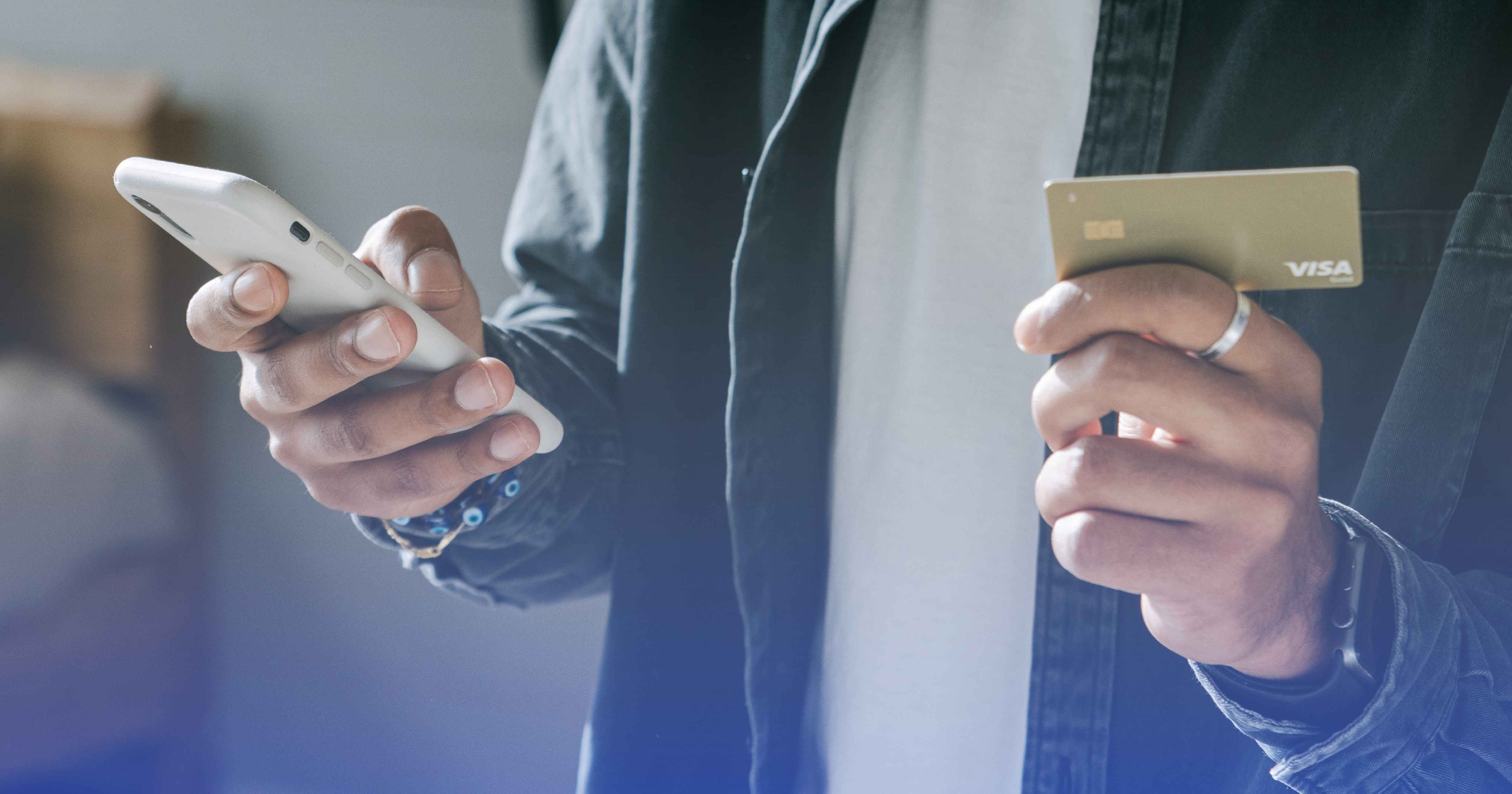 A close up of a man holding a credit card in his right hand and a cellphone in his left.